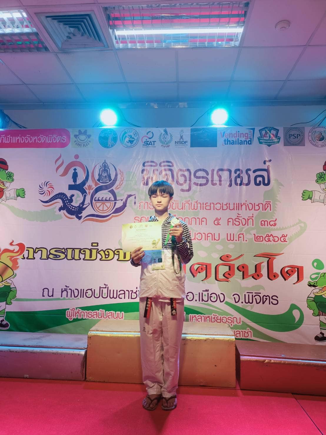 เด็กชายคุณากร ดีสมปรารถนา นักเรียนชั้นมัธยมศึกษาปีที่ 2/1 ที่ได้รับรางวัลชนะเลิศ เหรียญทอง การแข่งขันเทควันโด ประเภทต่อสู้ คาเด็ทชาย รุ่นน้ำหนักไม่เกิน 49 กก. การแข่งขันกีฬาเยาวชนแห่งชาติครั้งที่ 38 รอบคัดเลือก ภาค 5 "พิจิตรเกมส์" uploads/2/2022-12/2cd6859645f0041d326915dd69443519.jpg